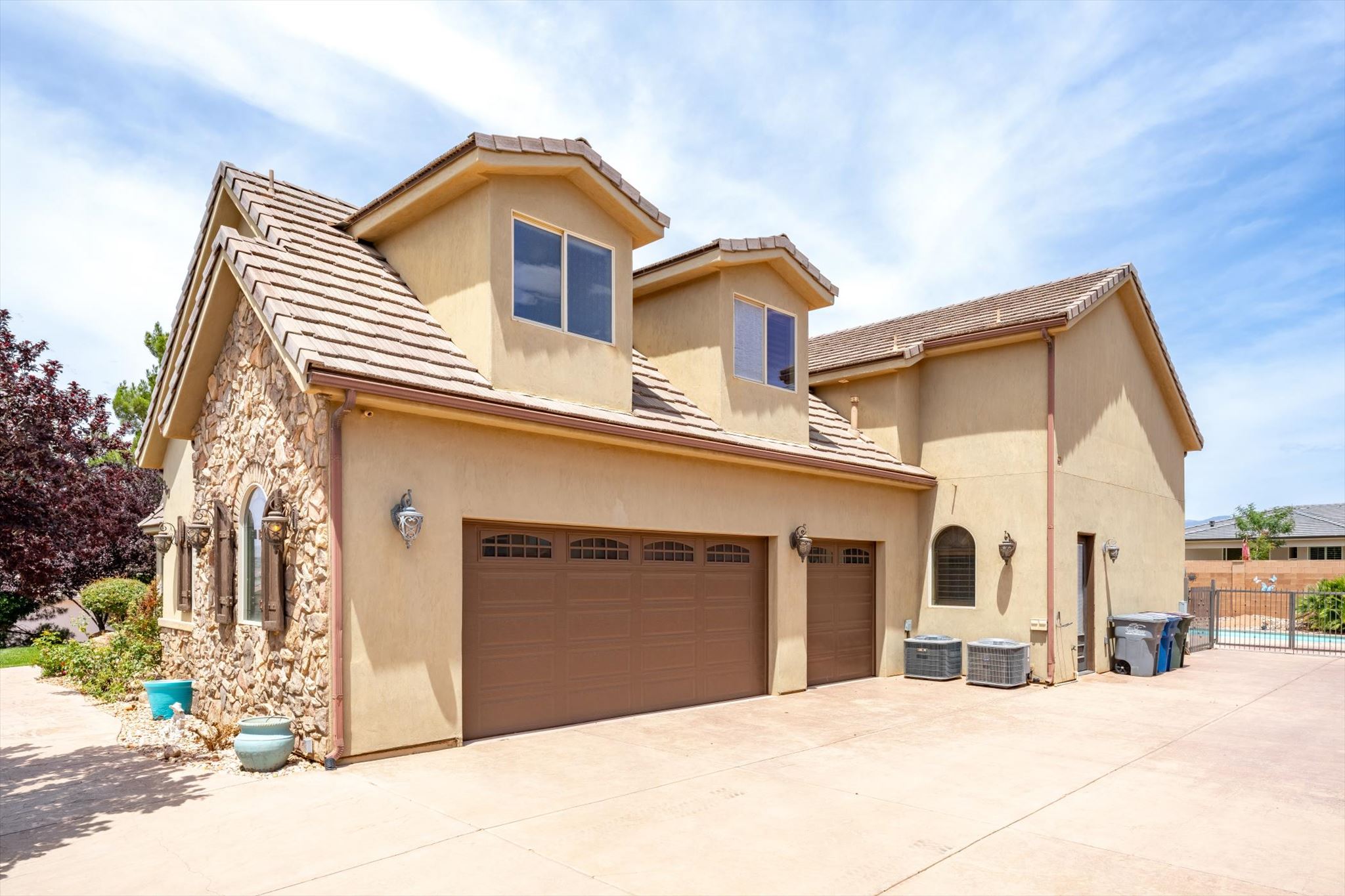 Stucco exterior with stone accents and a tiled roofline