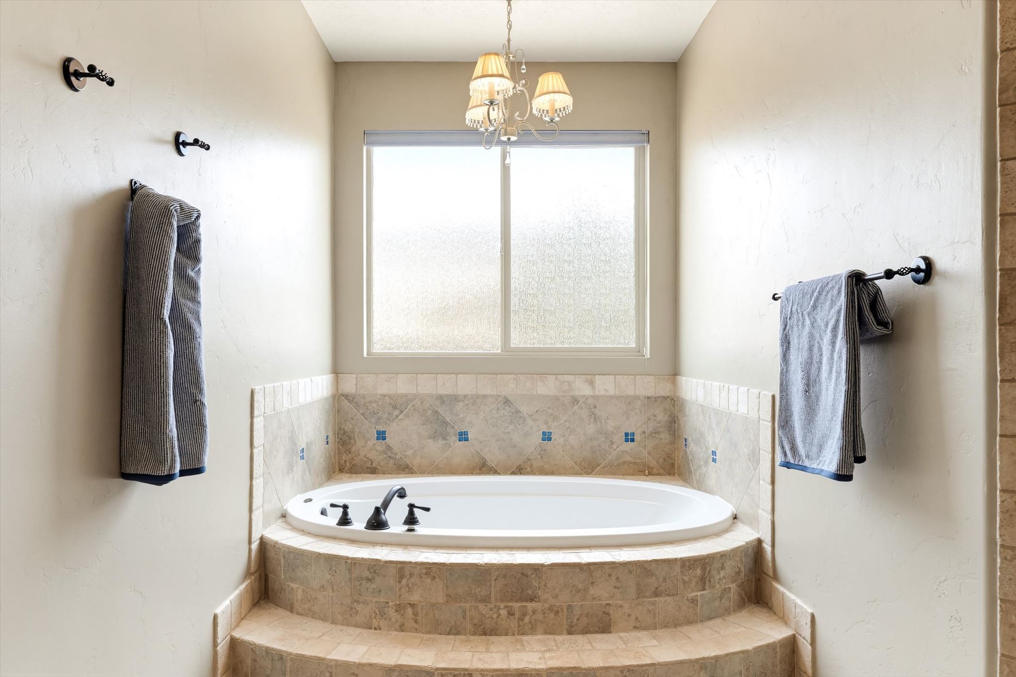 Oval soaking tub set within a tiled surround and stepped platform