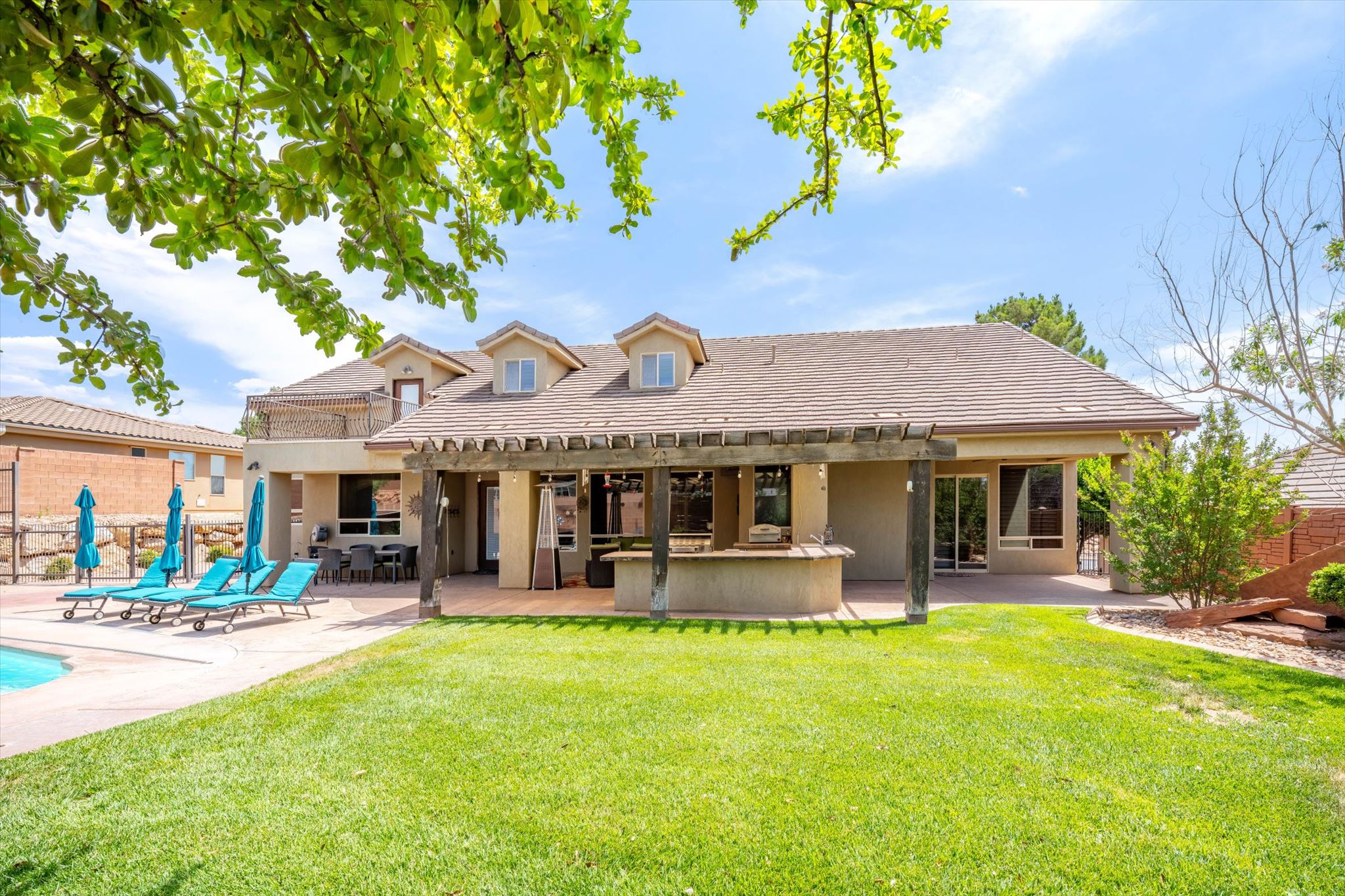 Expansive backyard featuring a manicured lawn, a large swimming pool, and an extensive patio