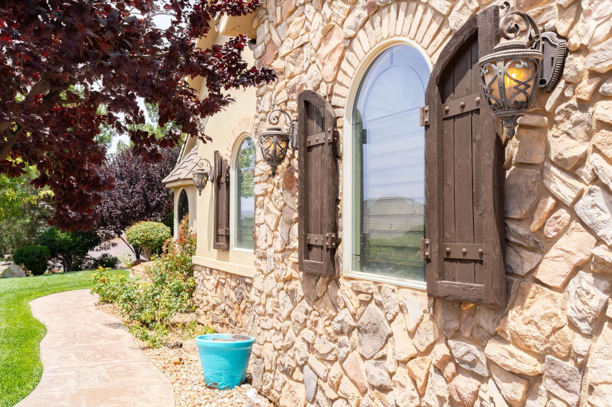 Stone facade exterior featuring arched windows, decorative shutters, and ornate wall-mounted lighting fixtures