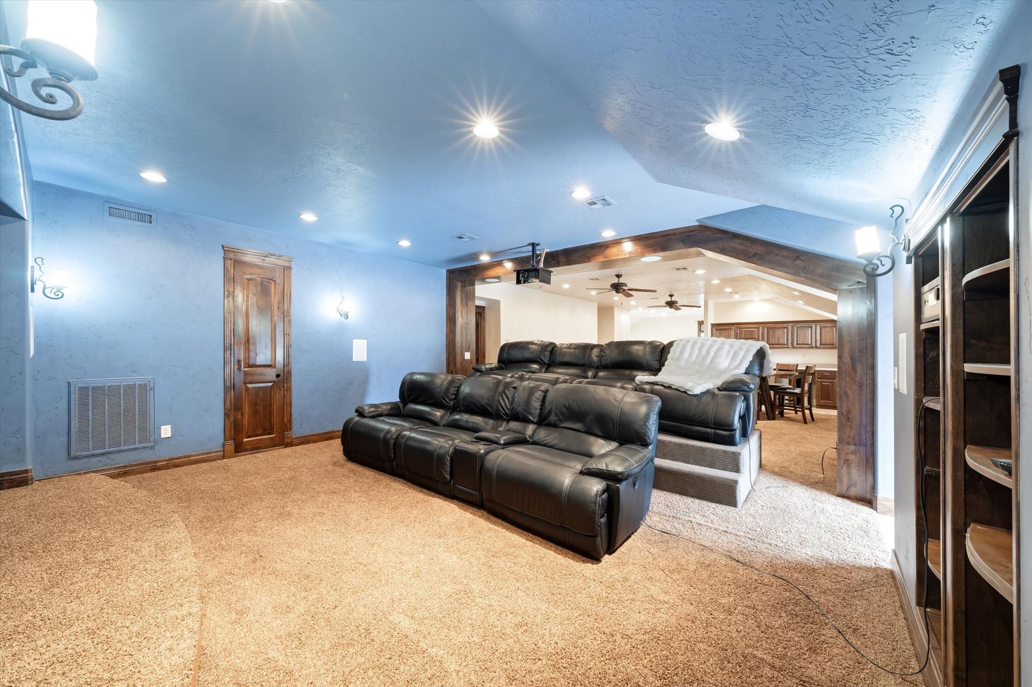 Recessed lighting illuminating a spacious carpeted area with a built-in shelving unit