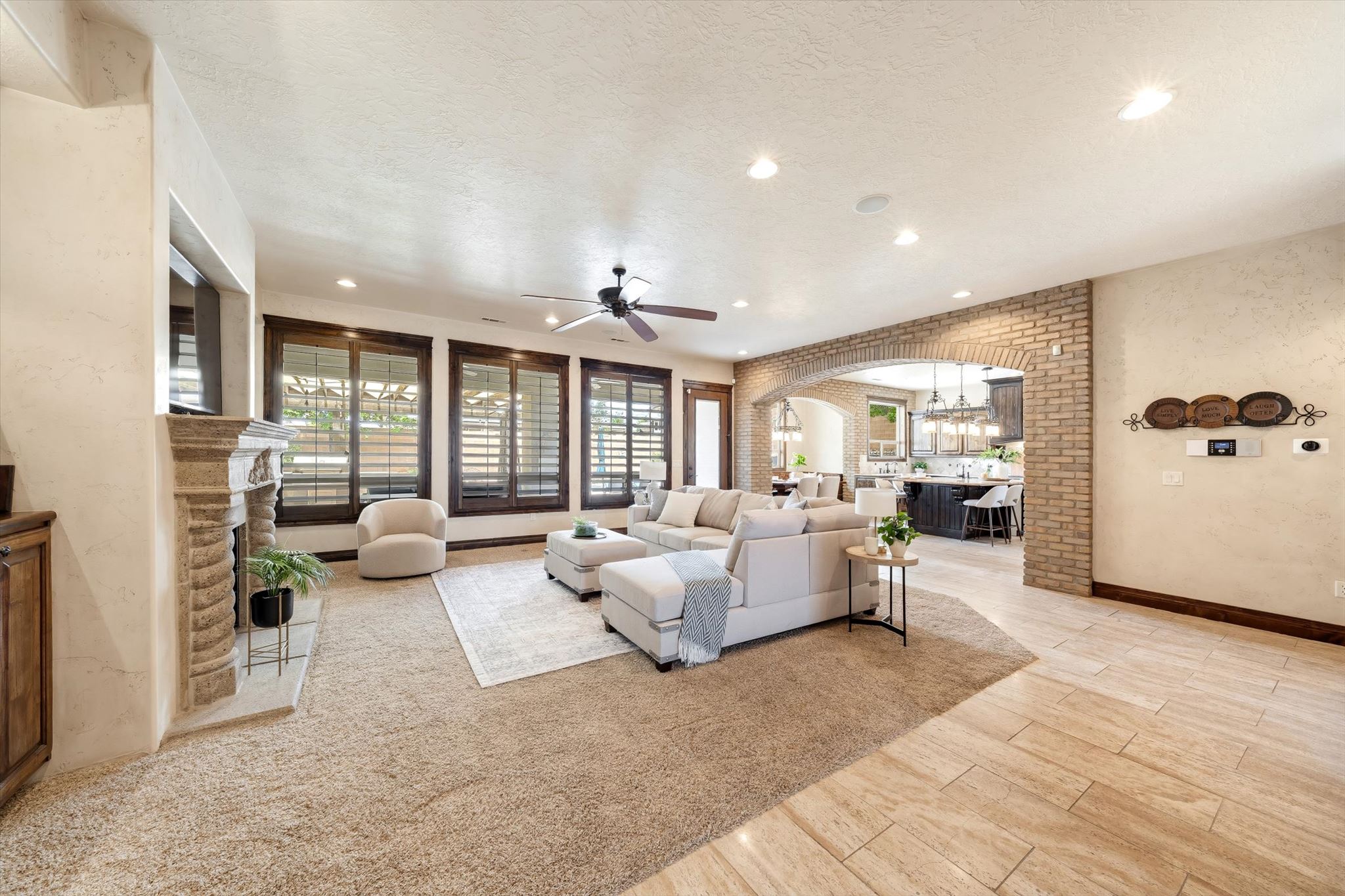 Spacious living area featuring a stone-clad fireplace and multiple windows with plantation shutters