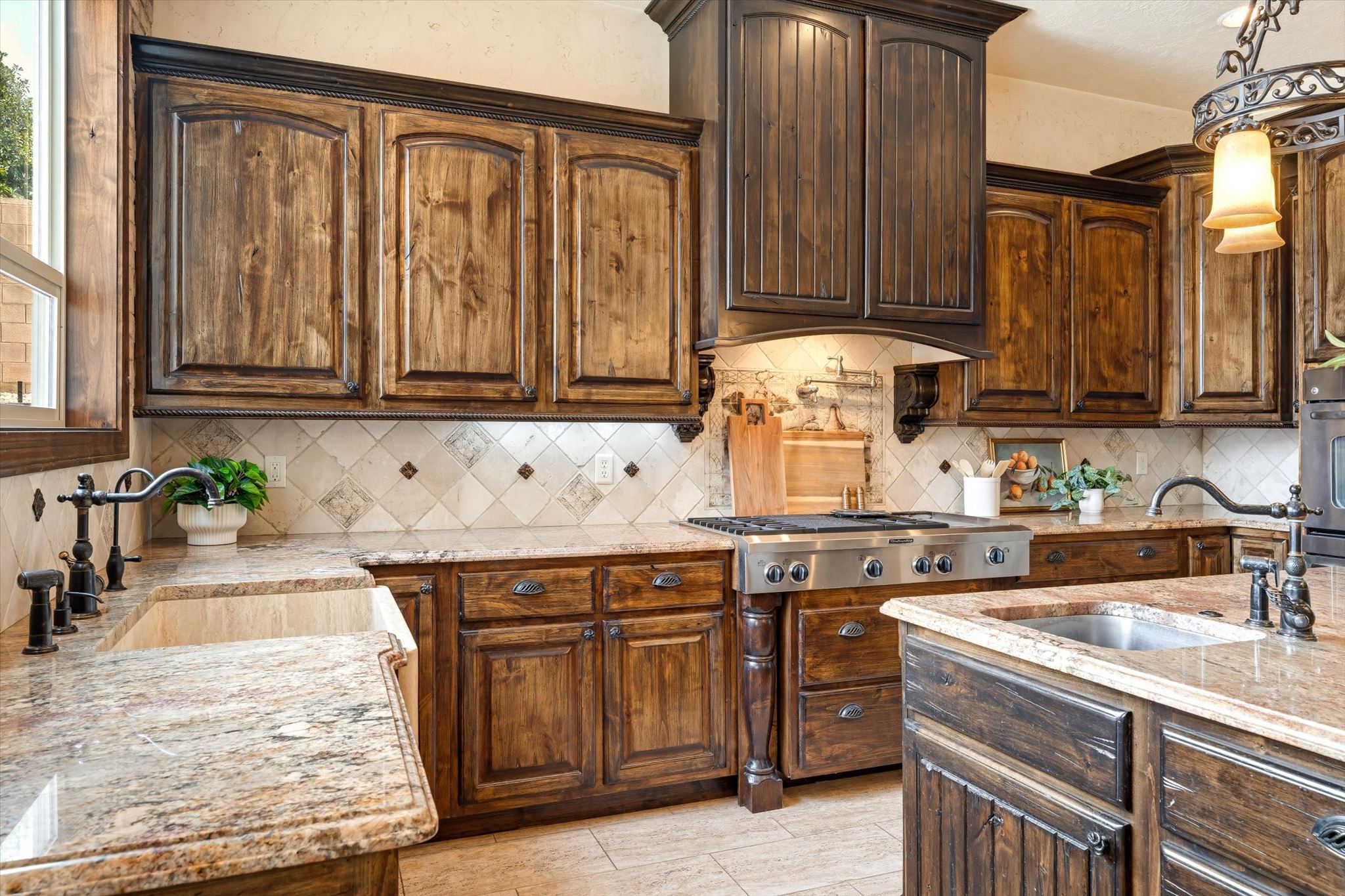 Kitchen showcasing wood cabinetry, light-toned stone countertops, and a full tile backsplash