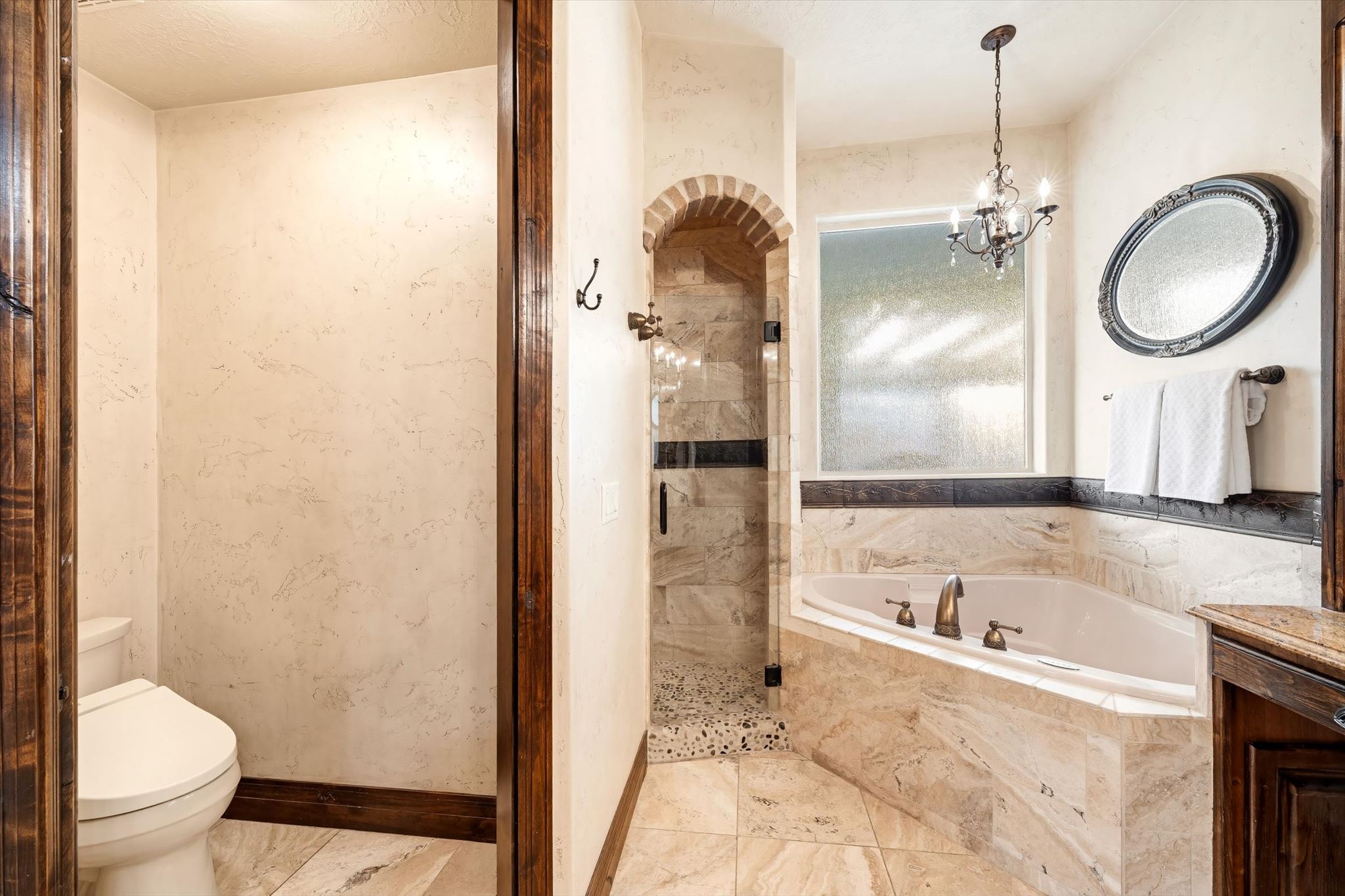 Bathroom featuring a built-in tub with a bronze faucet, tile surround, and an arched shower entry