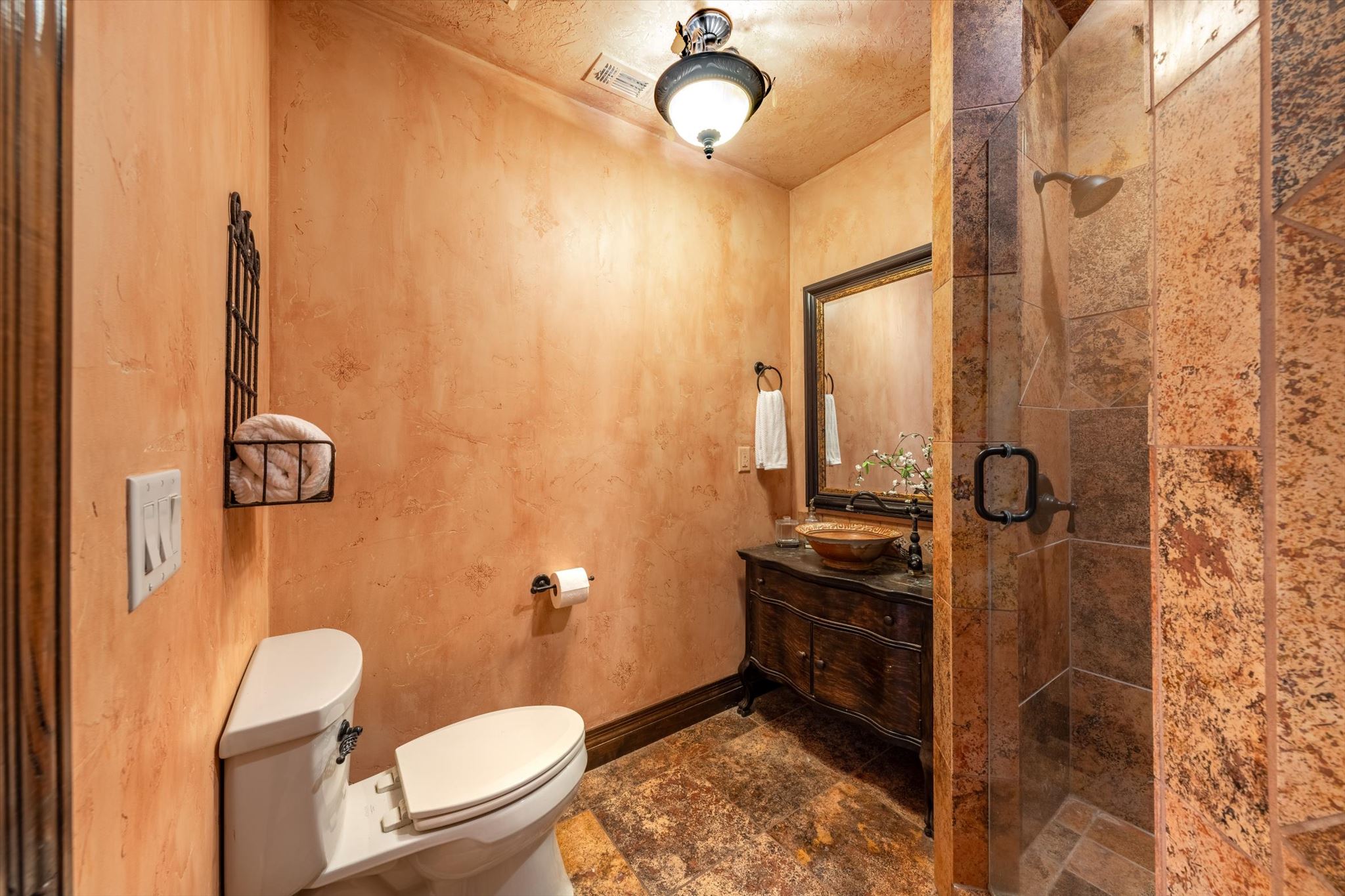 Bathroom featuring a walk-in shower with stone tile, a glass enclosure, and a rain showerhead
