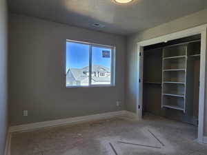 Bedroom featuring a window with a neighborhood backdrop, warm neutral wall paint, white trim, a flush-mount ceiling light, and a closet with built-in shelving