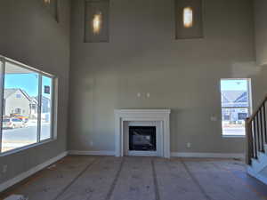 Two-story living area featuring a white mantel fireplace, large windows, recessed wall lighting, and a staircase with wood handrails and black balusters