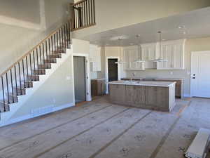 Open-concept kitchen and living area featuring a central island with wood-finish cabinetry, a large sink, and three pendant lights
