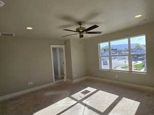 Spacious room featuring multiple recessed ceiling lights, a bronze and black ceiling fan, and a large multi-pane window