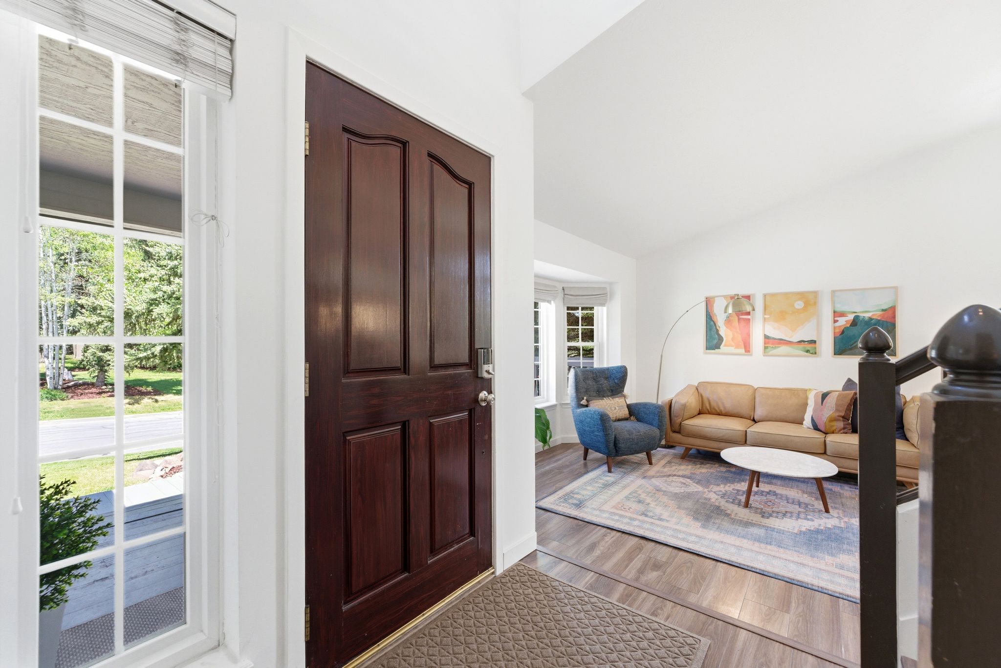 Foyer featuring a paneled entry door, sidelight window, LVP flooring, and a vaulted ceiling