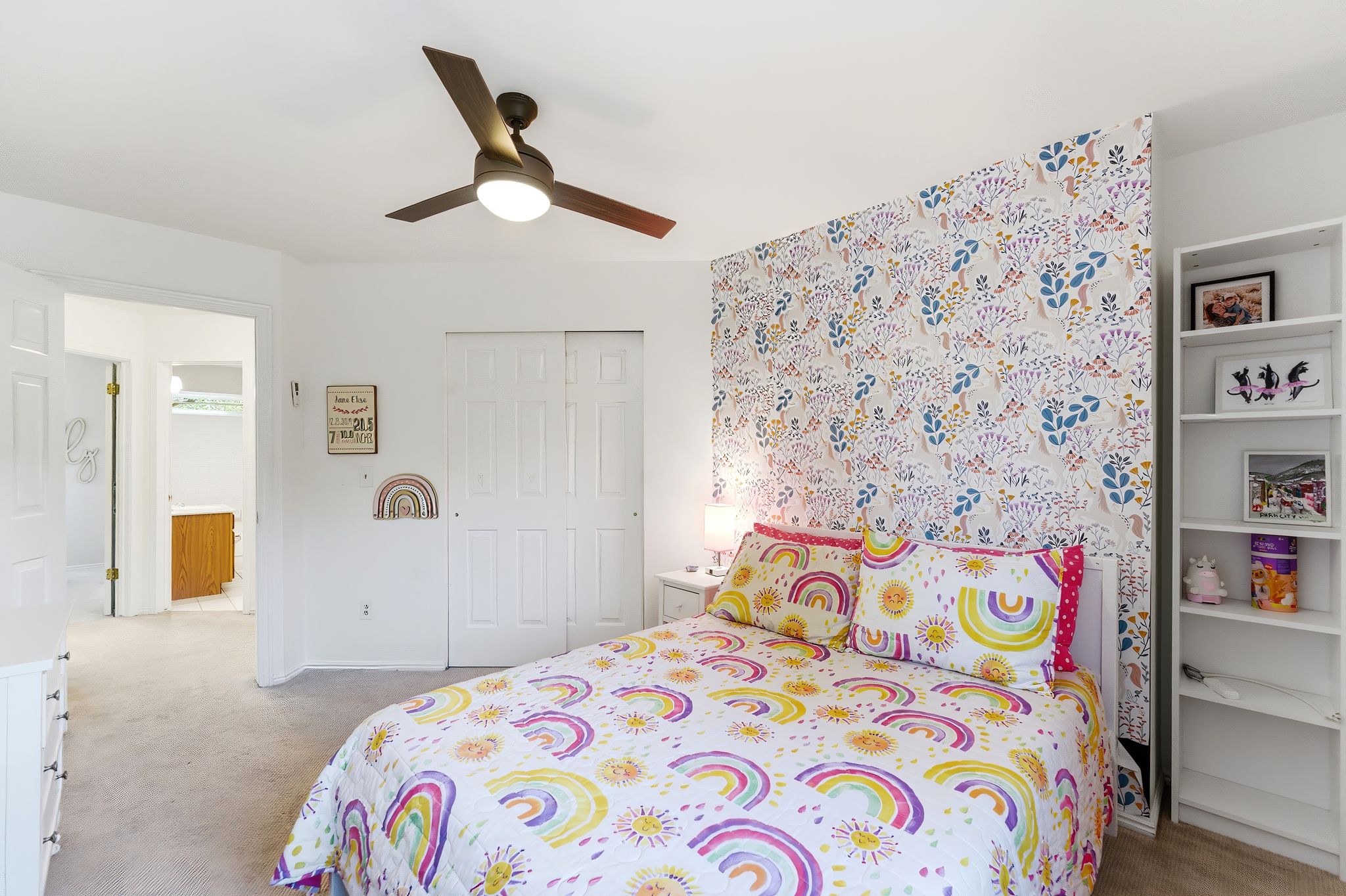 Upper Bedroom 2 featuring a decorative accent wall, ceiling fan with integrated lighting, built-in shelving, carpet flooring, and sliding closet doors