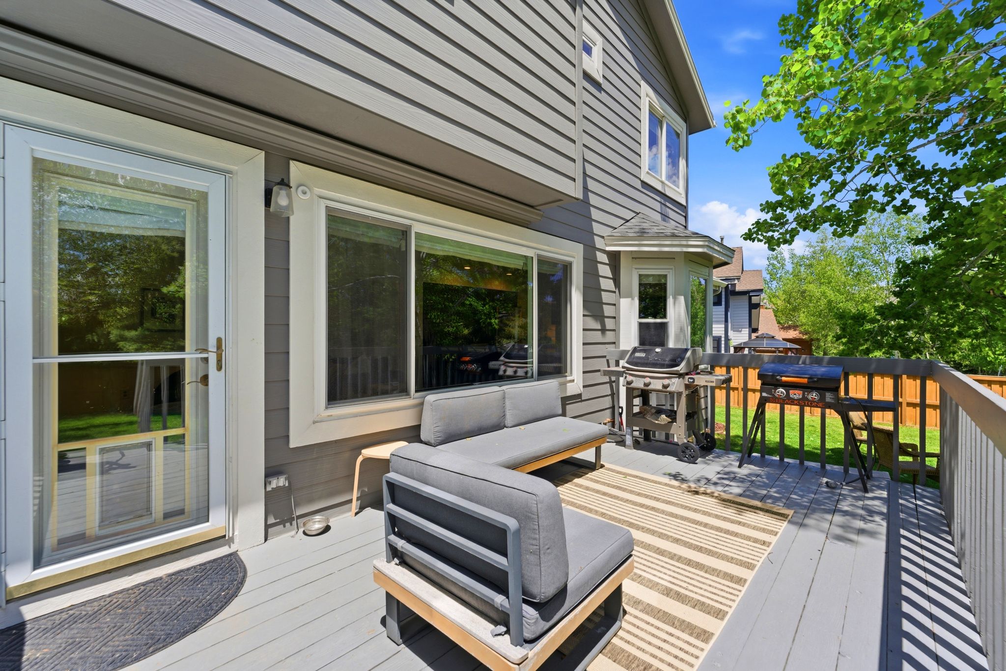Rear Yard with Expansive outdoor deck featuring composite decking, white-trimmed window, and a glass-paneled storm door