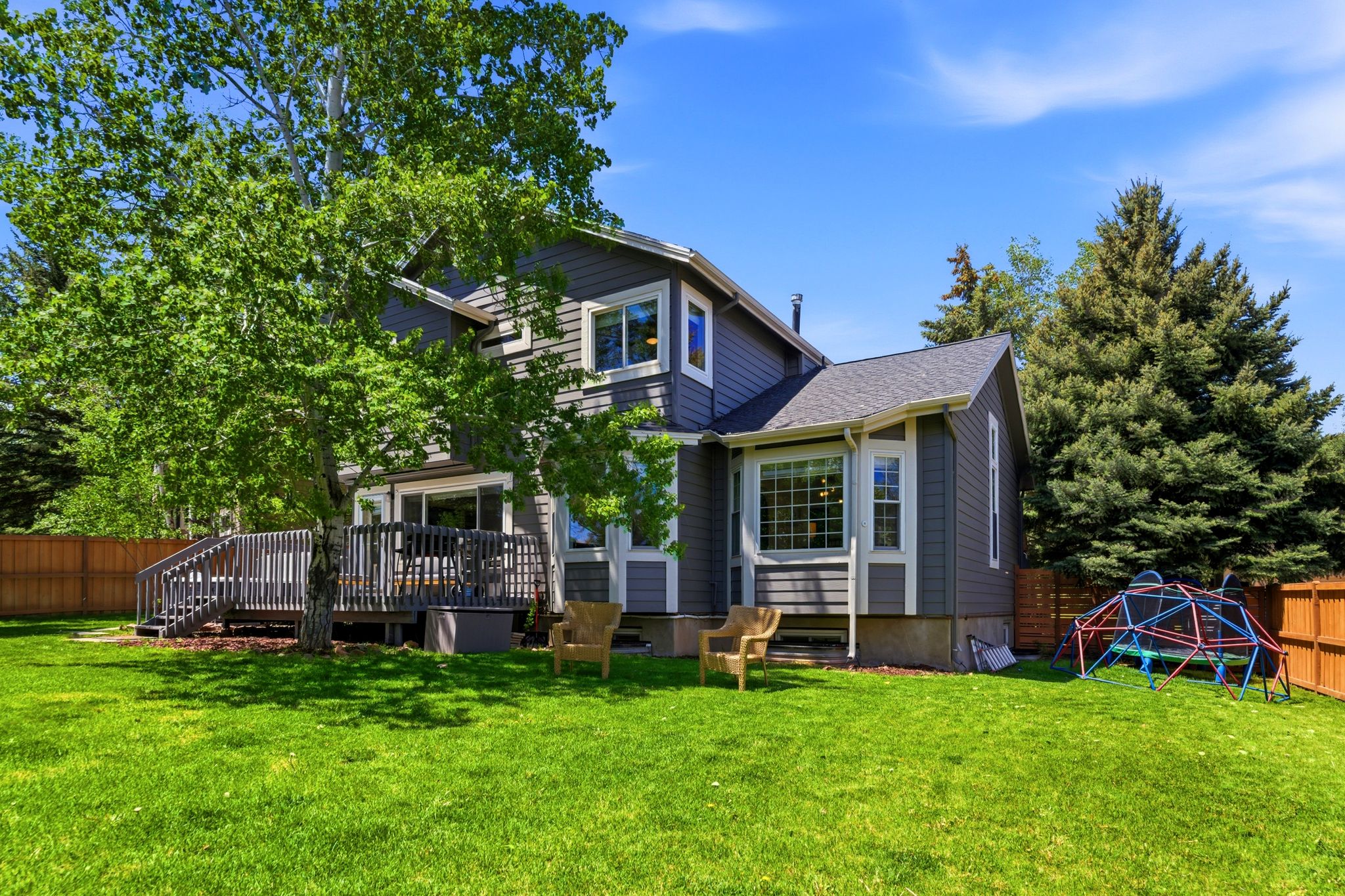 Rear yard with Expansive green lawn with mature trees and a substantial wood deck
