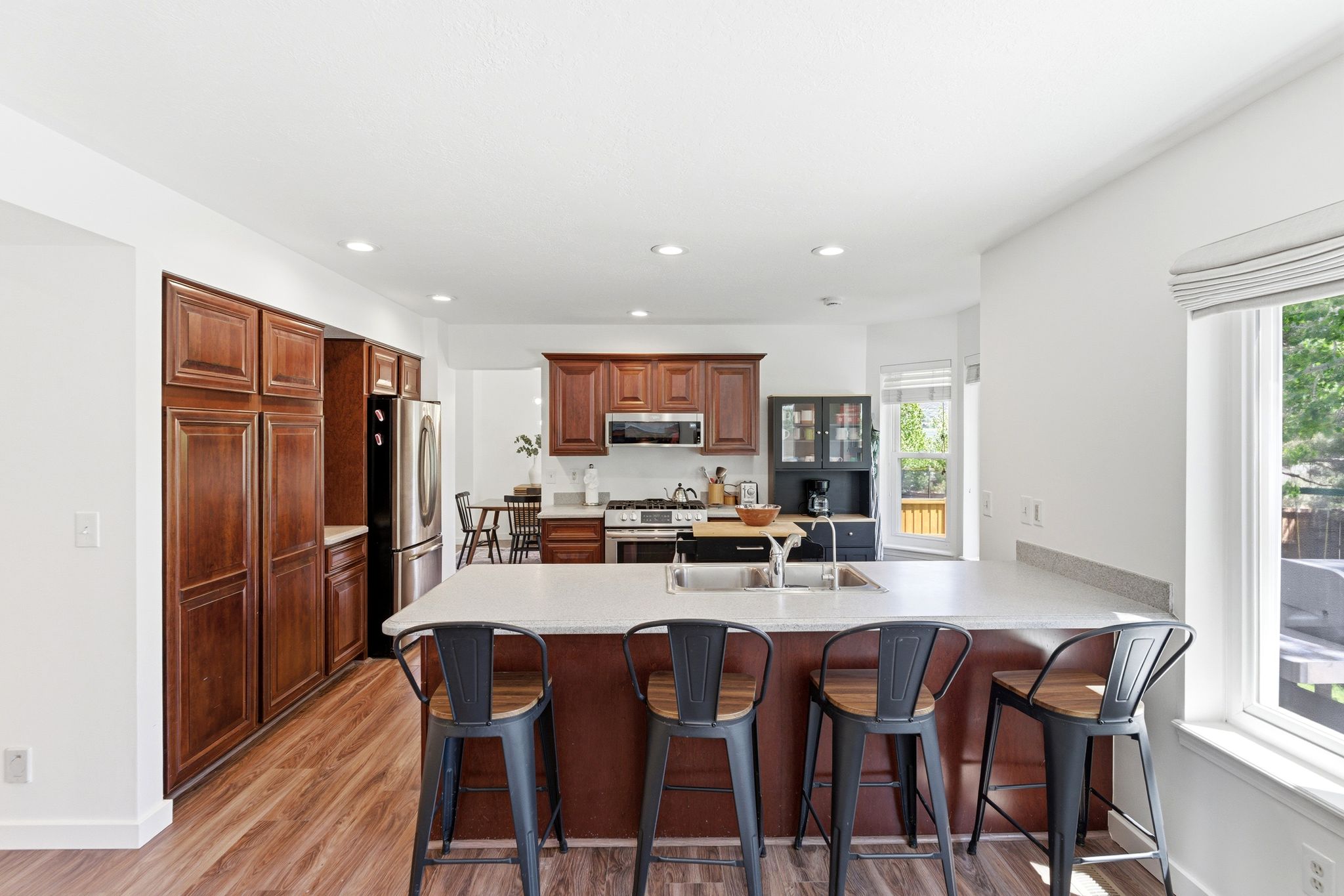 Kitchen featuring a central island with a light-toned countertop, wood-finish flooring, recessed lighting, stainless steel appliances, and abundant wood cabinetry