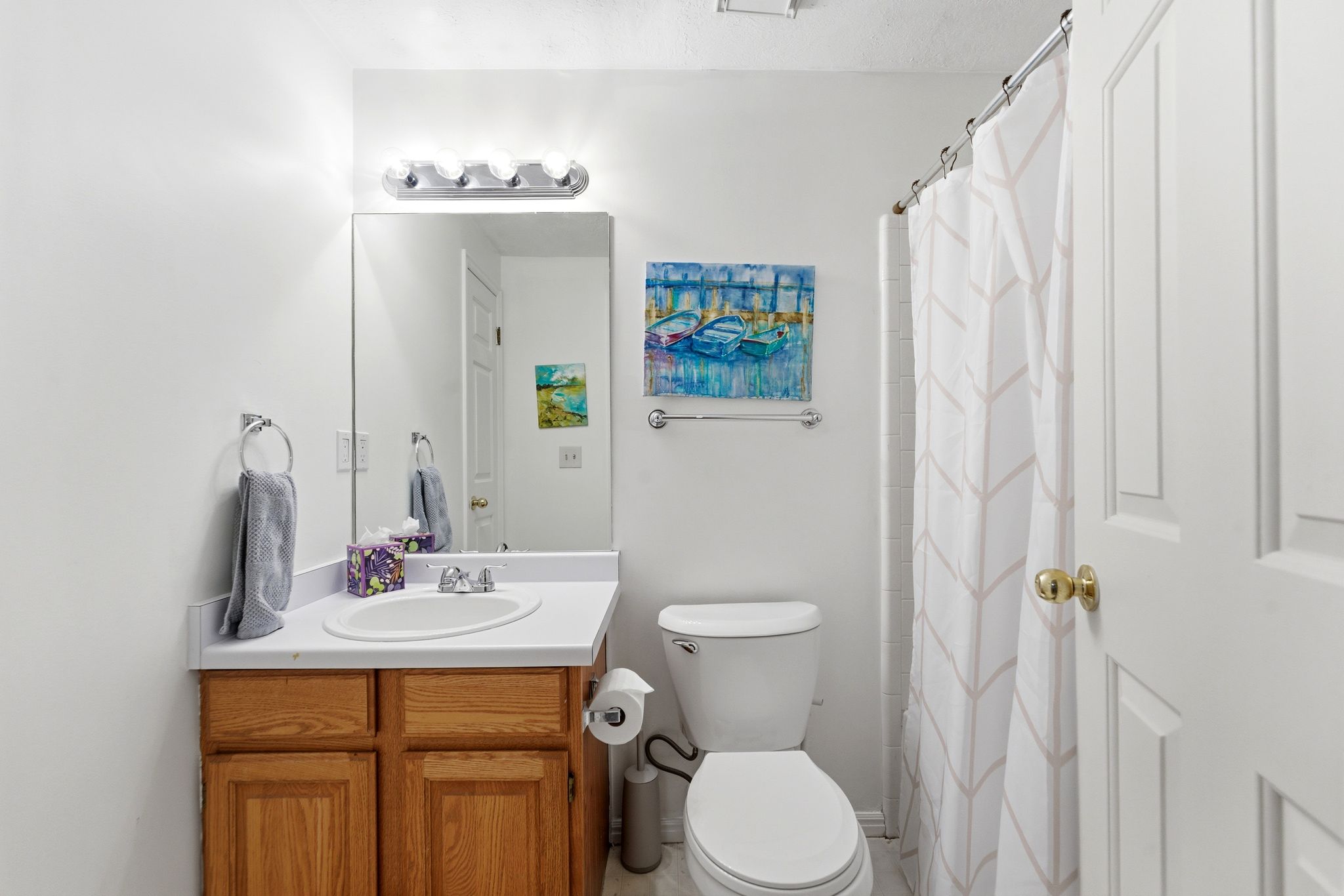 Lower Level hall Bathroom featuring a single vanity with wood-finish cabinetry, a white countertop, and a built-in sink