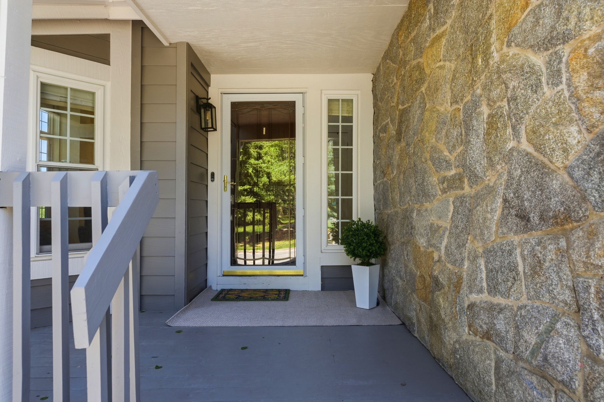 Stone facade exterior featuring a covered porch with painted railings