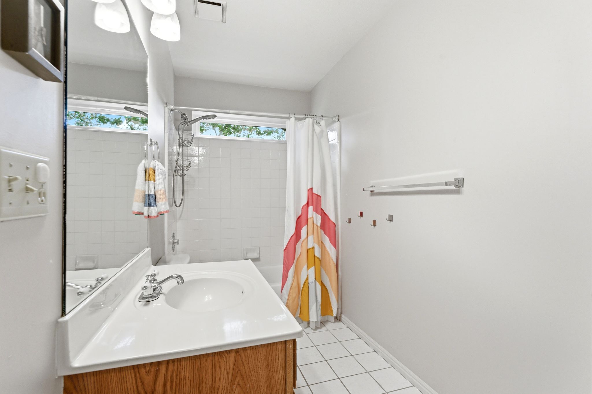 Upper Hall Bathroom featuring a wood-finish vanity with an integrated sink, a large mirror, and overhead lighting