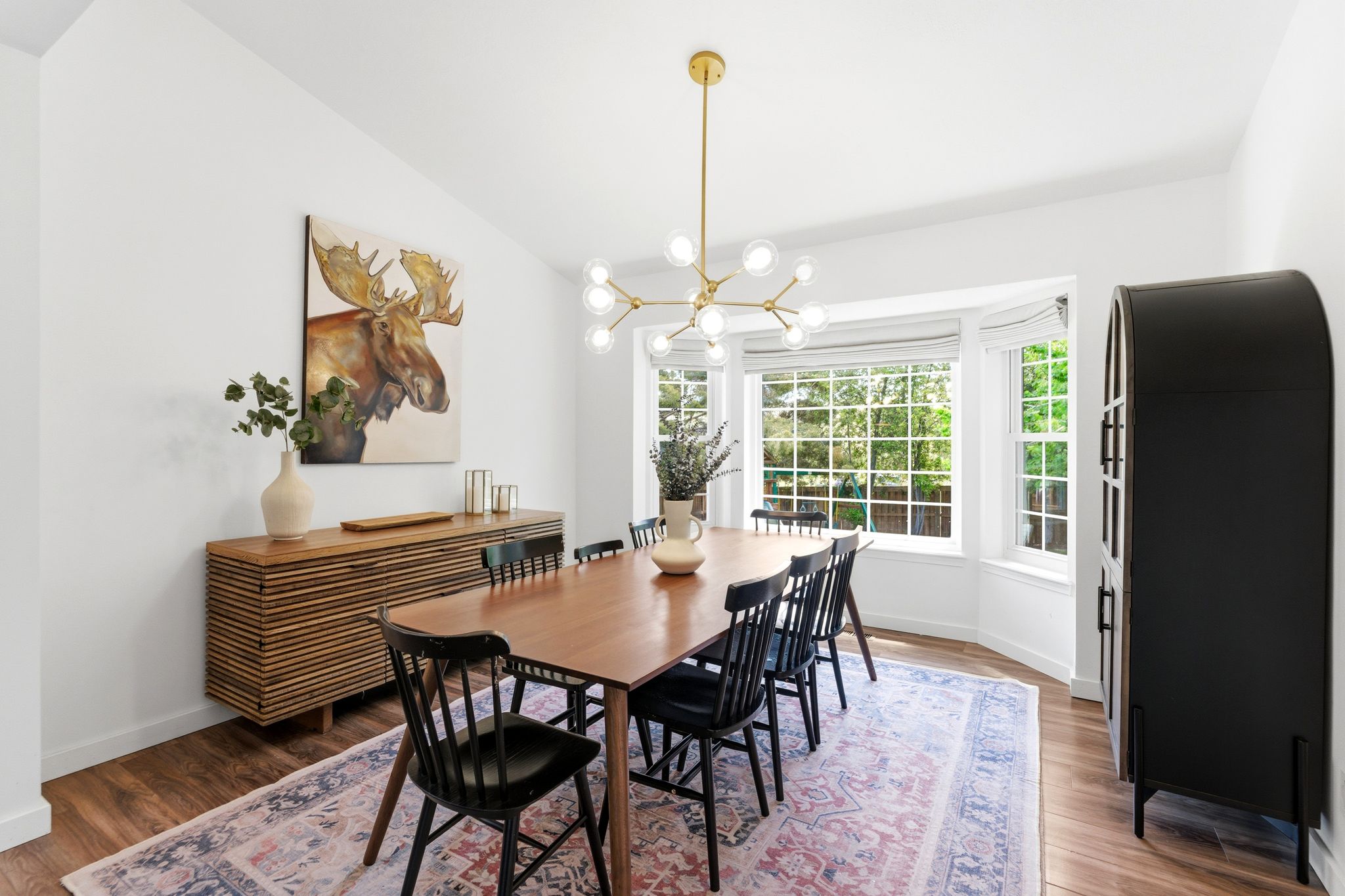 Bay window dining area featuring LVP flooring, a modern chandelier, and ample natural light