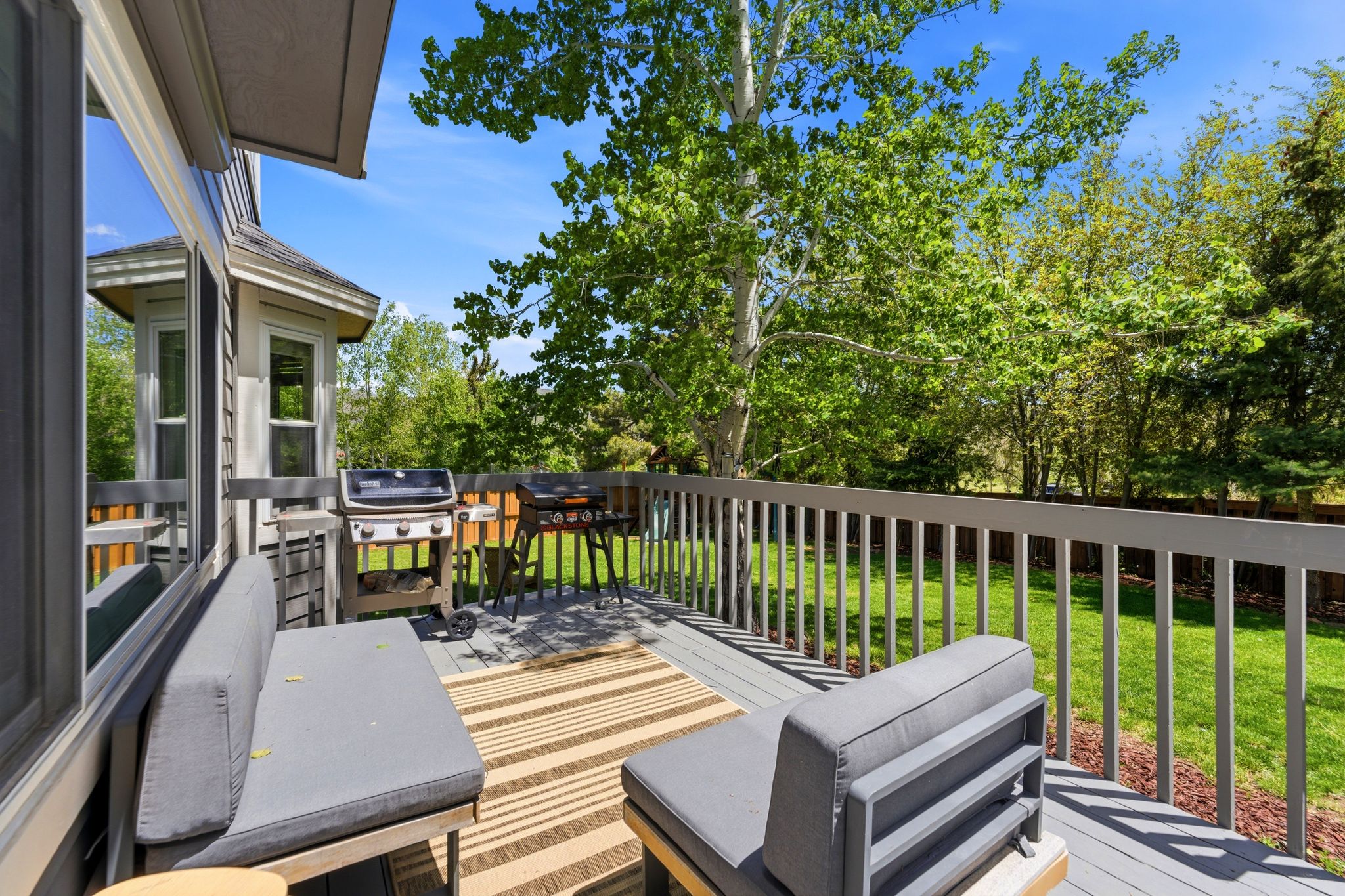 Rear Fenced yard with Expansive rear deck featuring gray wood-finish flooring and a matching railing