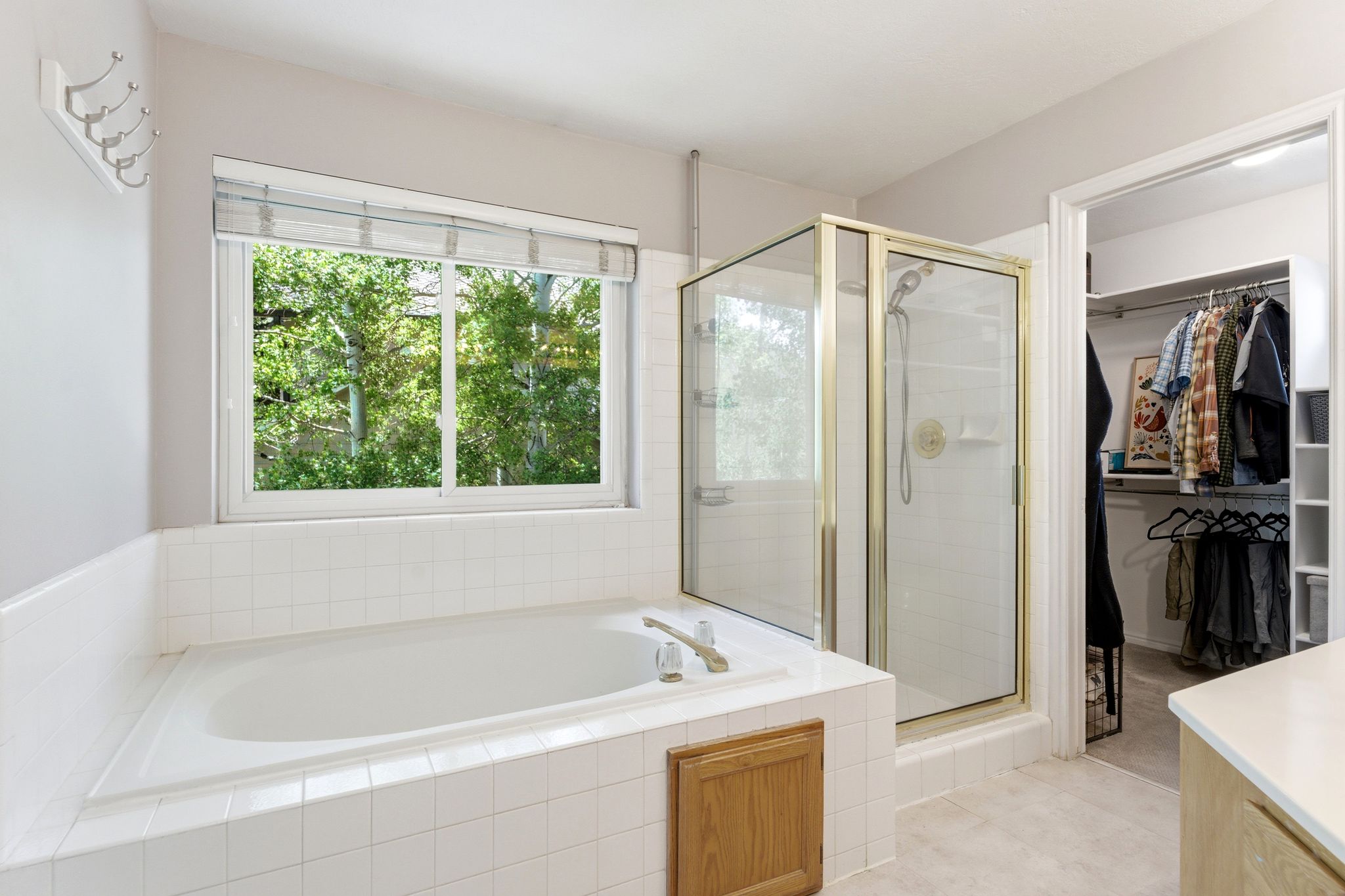 Upper Primary Bath with Soaking tub with white tile surround, glass-enclosed shower, and a built-in organized closet