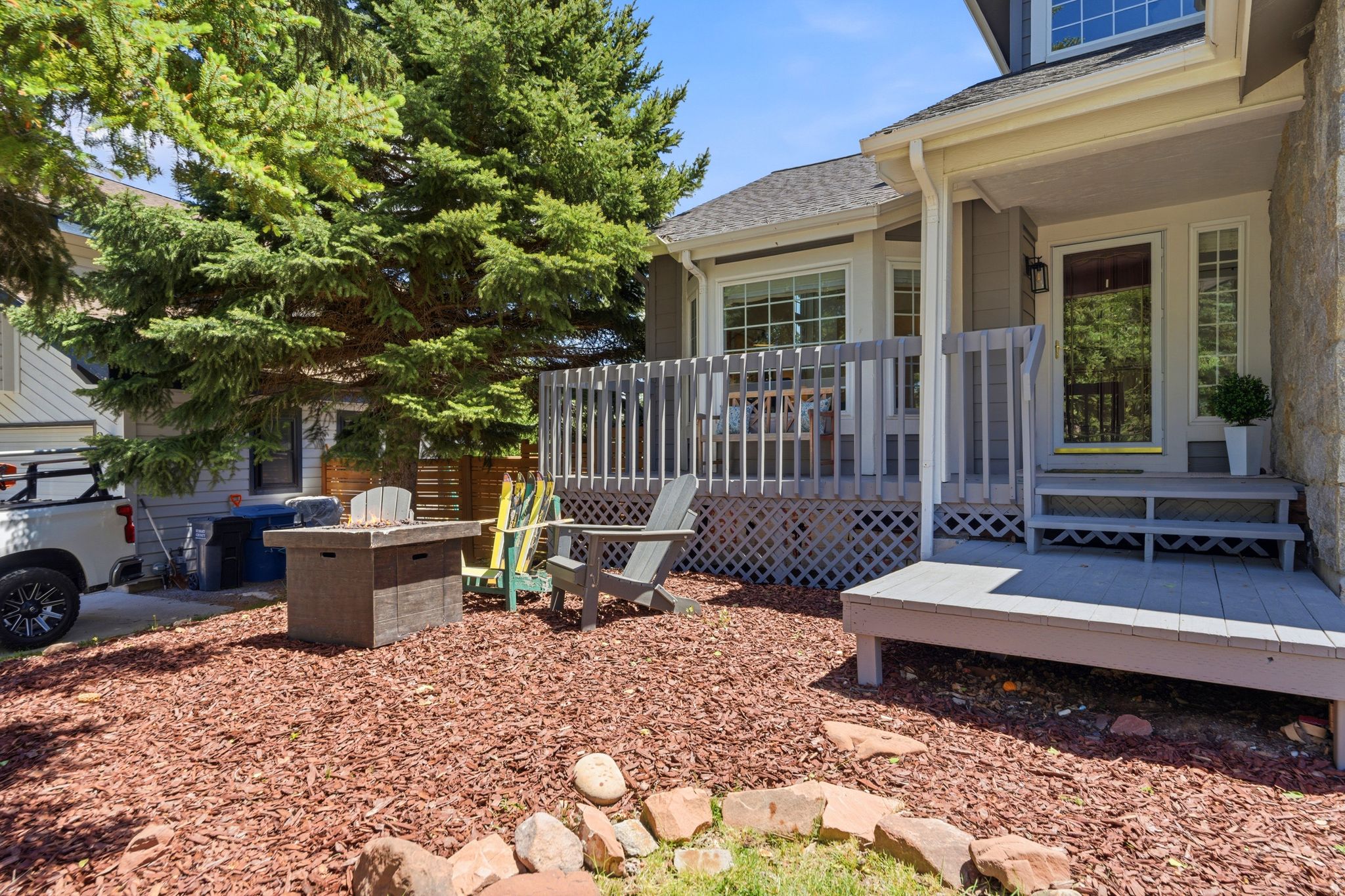 Expansive outdoor living area featuring a multi-level deck, a lower patio, and a stone-clad fire pit