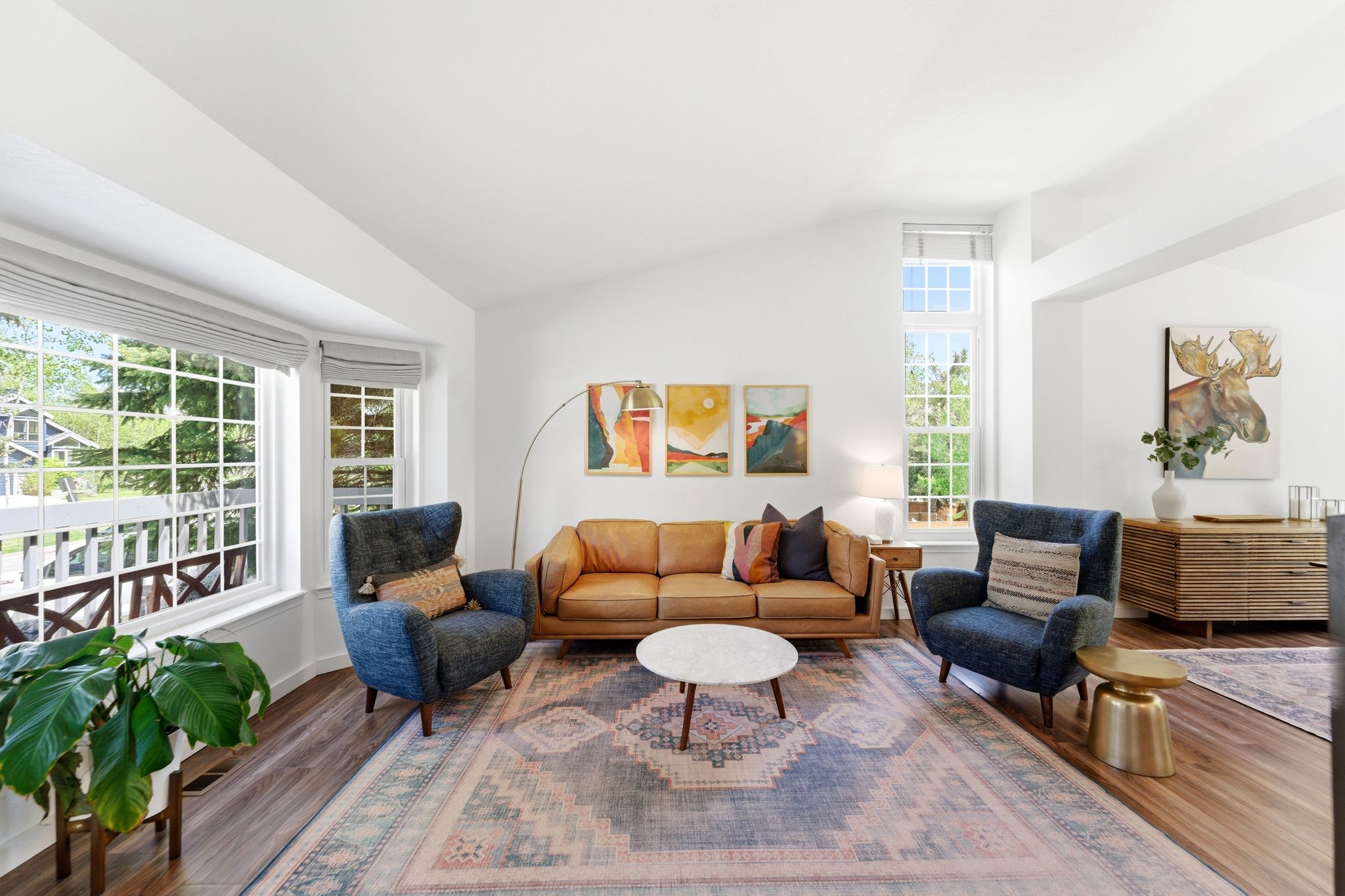 Open-concept living area featuring vaulted ceilings, LVP flooring, a prominent bay window, and additional tall windows providing abundant natural light