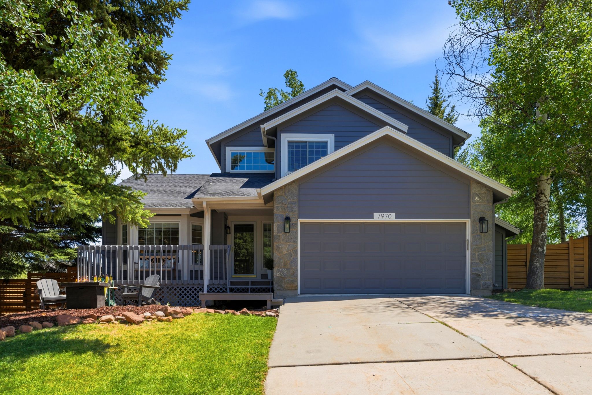 Multi-level residence featuring gray siding, stone accents, and a two-car garage