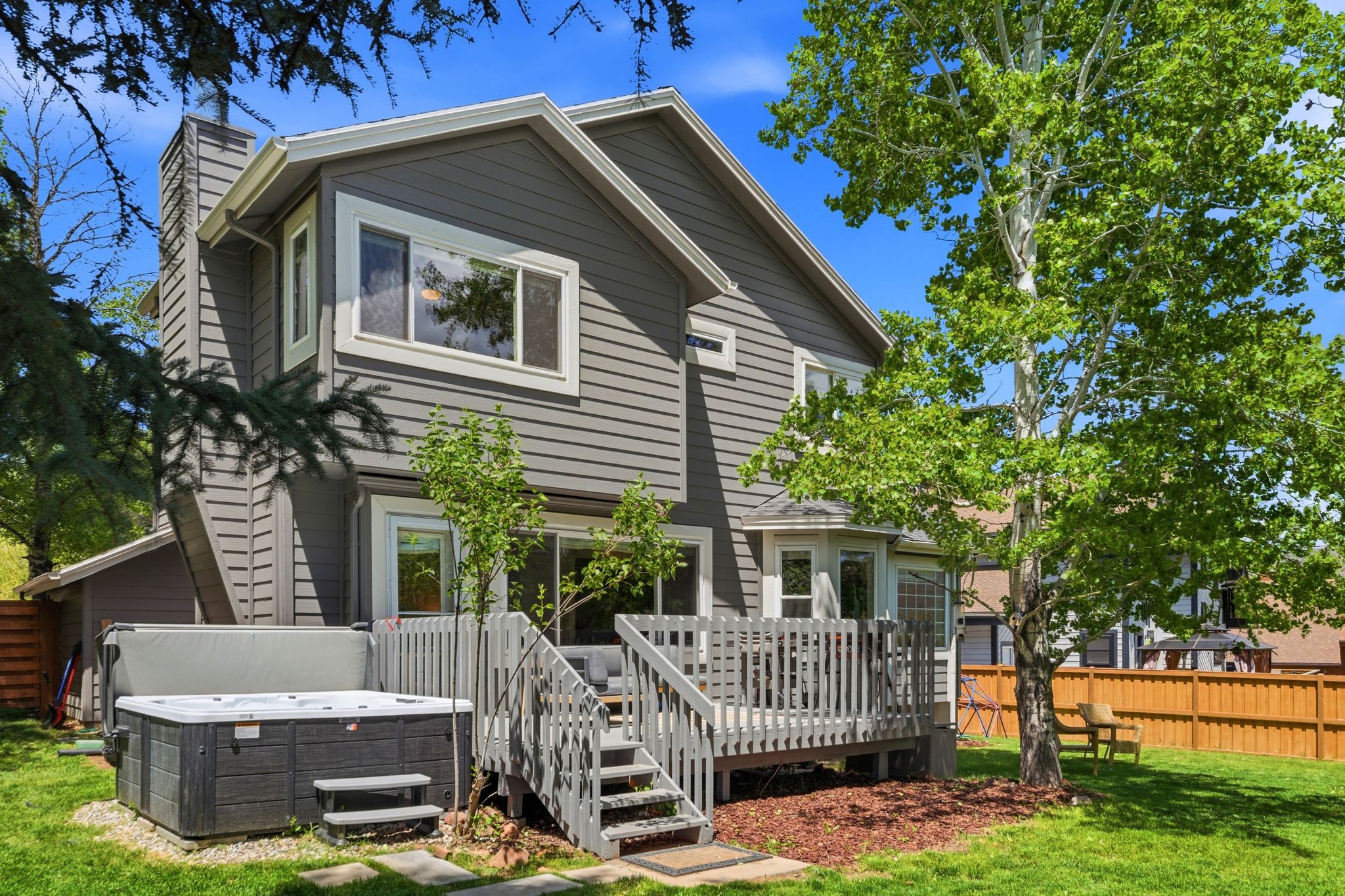 Exterior siding featuring multiple windows, a rear deck, a built-in spa, a bay window, and a fenced backyard