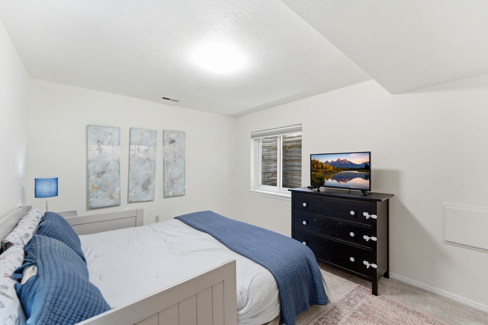 Brightly lit room featuring neutral wall paint, a single window, and textile flooring