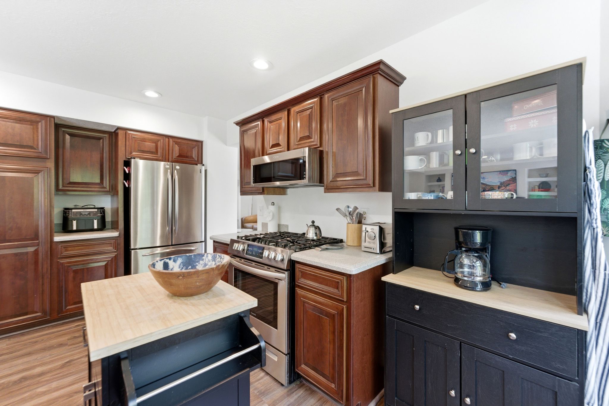 Kitchen featuring LVP flooring, recessed lighting, stainless steel appliances, and wood cabinetry with crown molding
