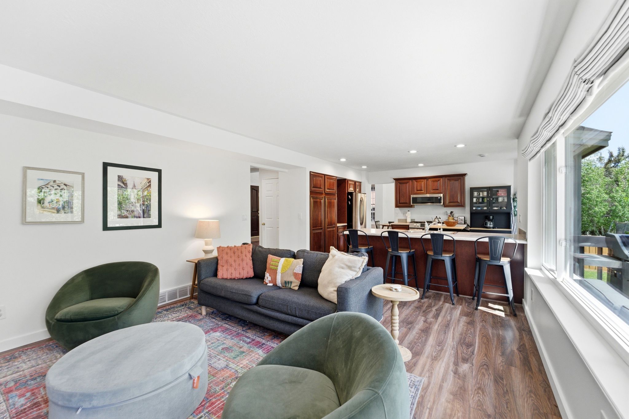Open-concept living space featuring LVP flooring, white walls, and abundant natural light from large windows