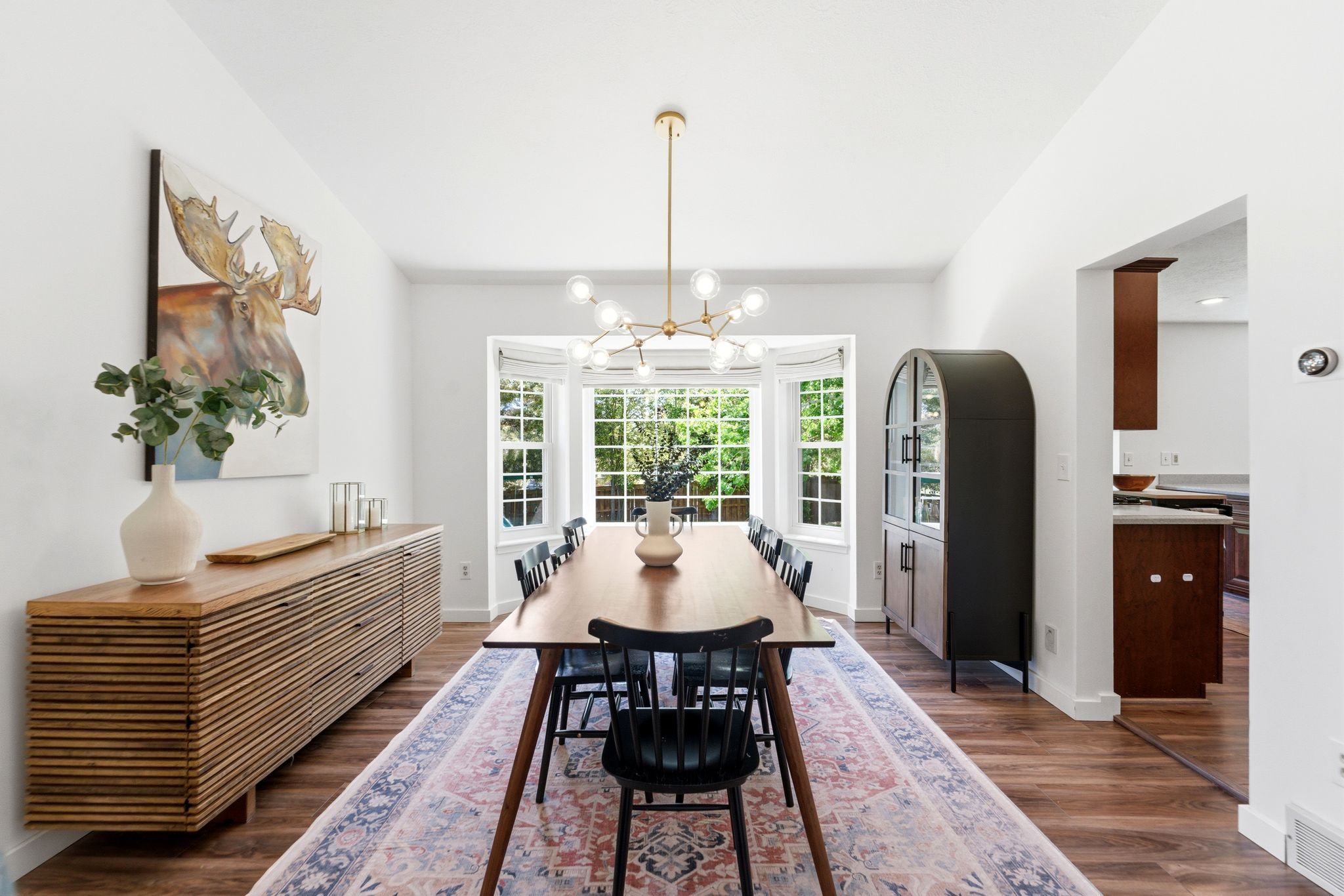 Bright dining area featuring a bay window, LVP flooring, and a contemporary chandelier