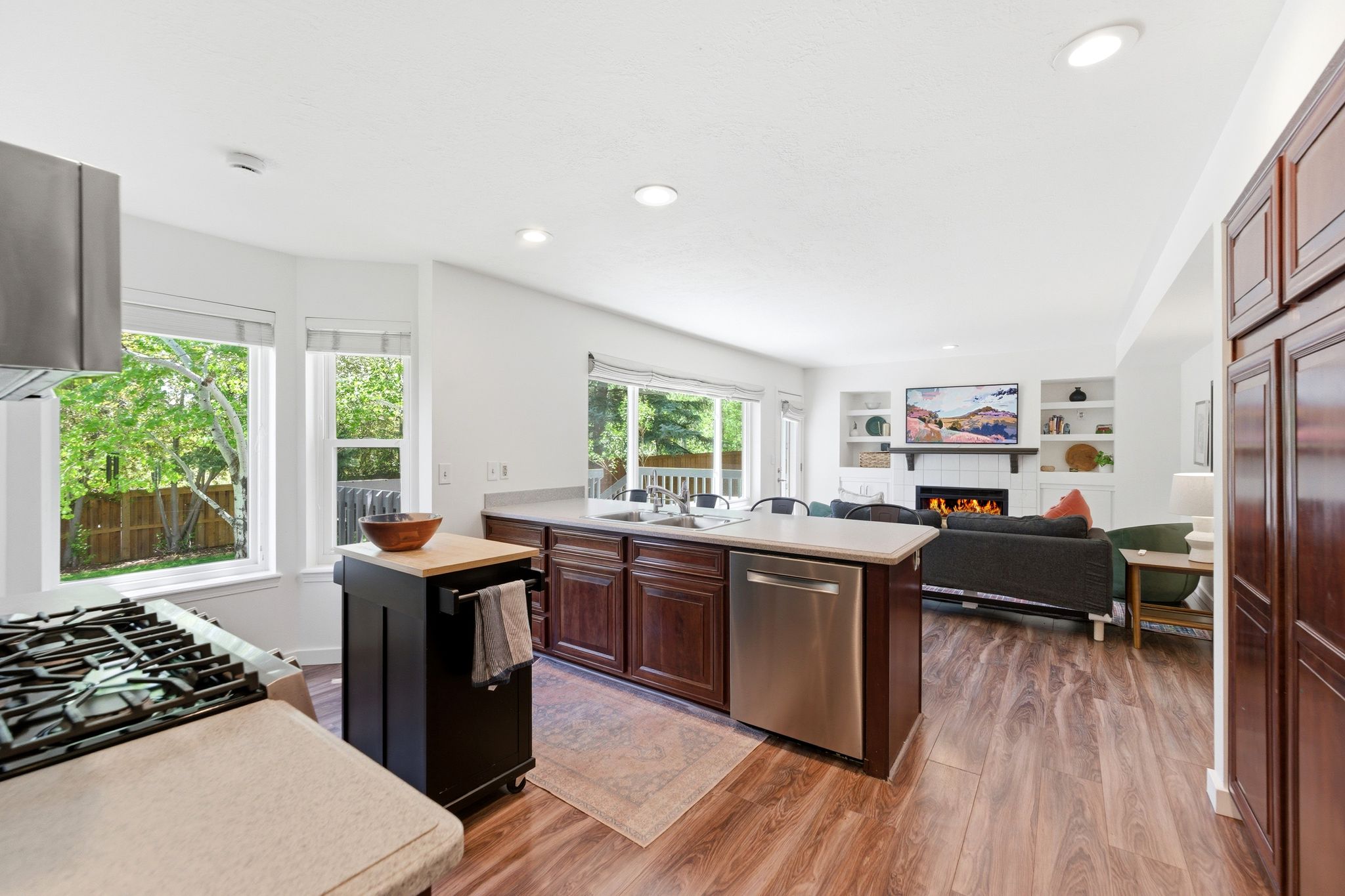 Open-concept kitchen and living area featuring LVP flooring, recessed lighting, and a kitchen island with integrated sink