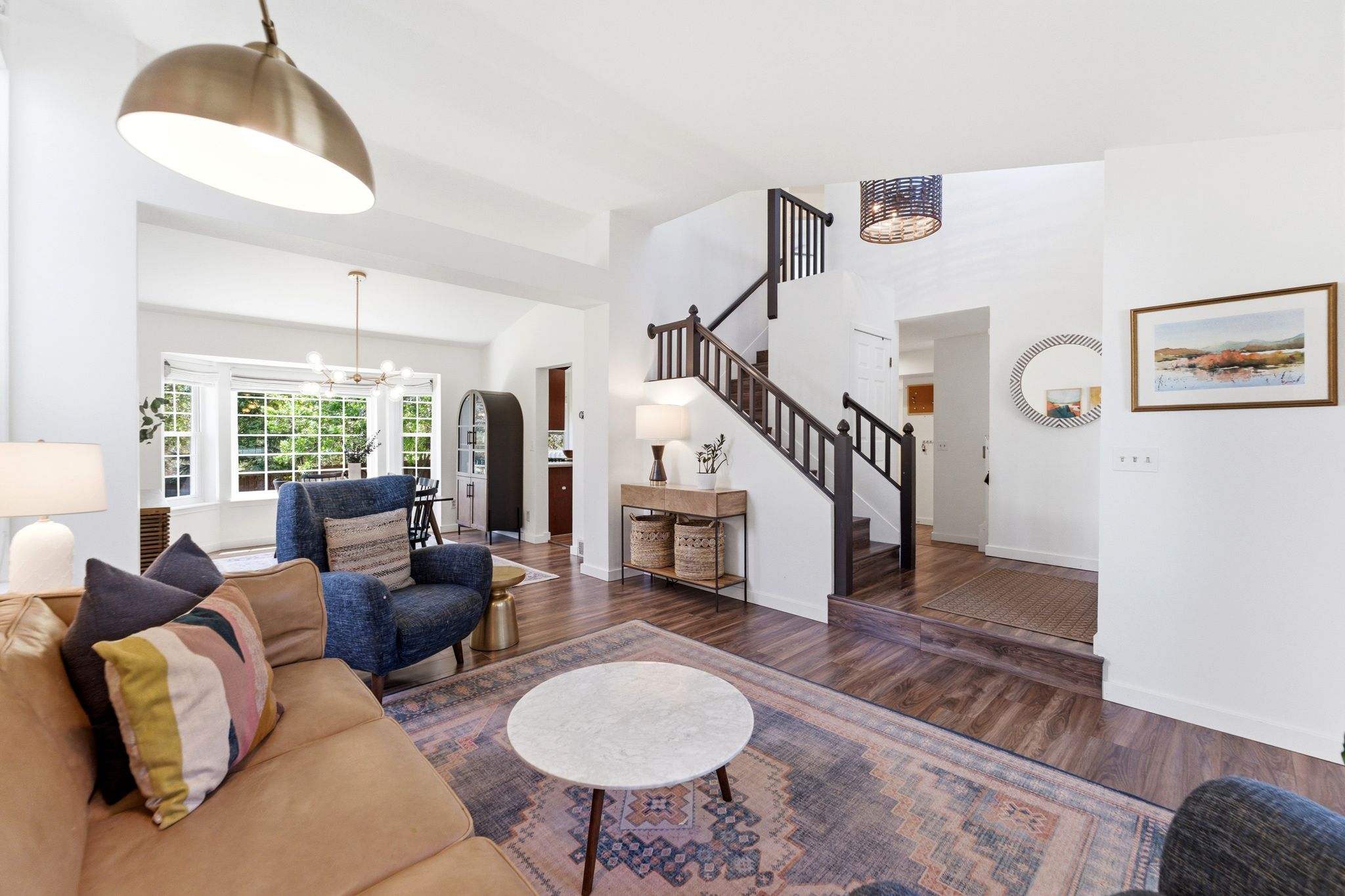 Spacious living area featuring LVP flooring, a prominent staircase with dark wood railing, and an open concept layout
