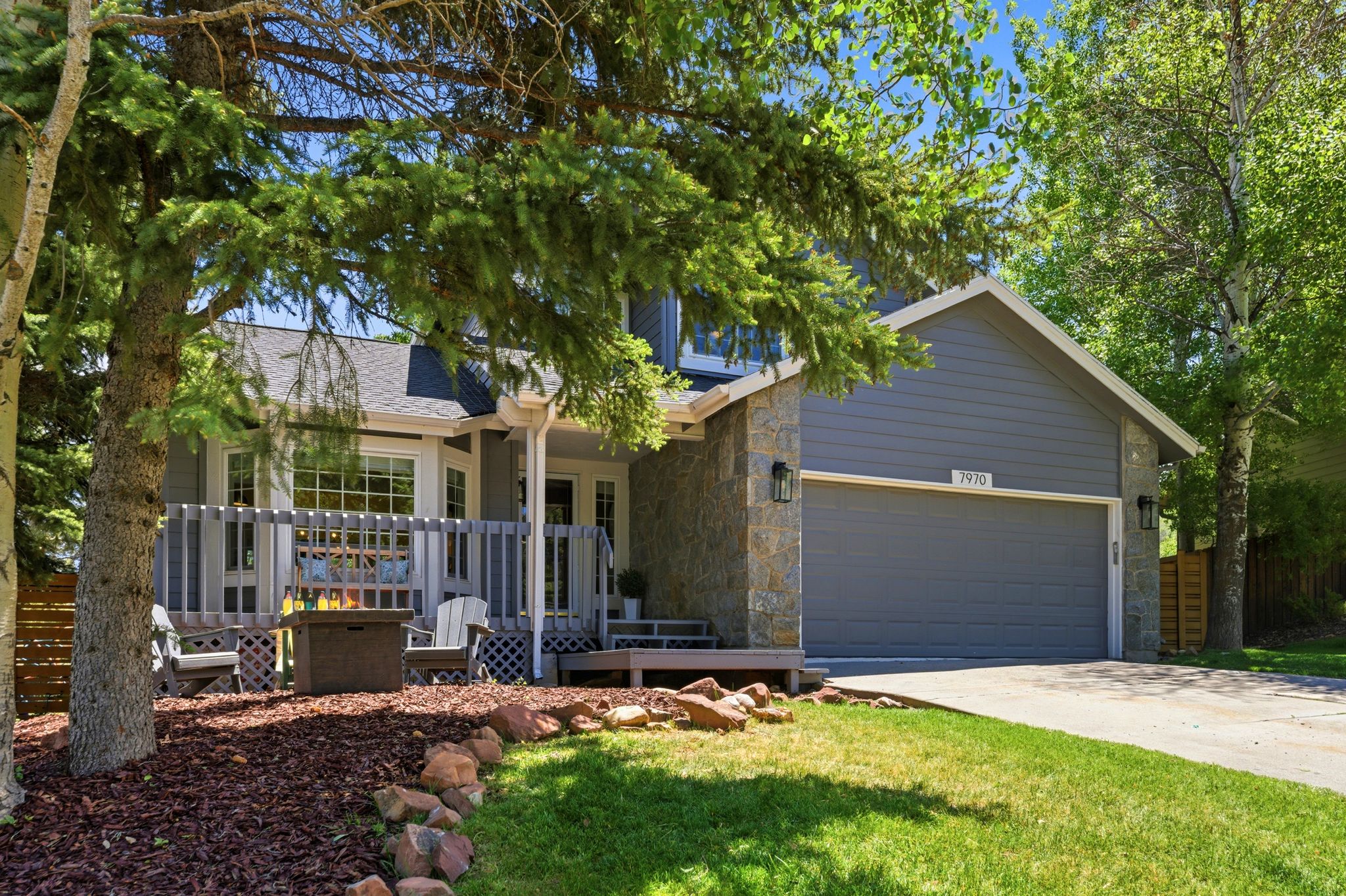 Contemporary residence featuring grey siding and stone veneer accents