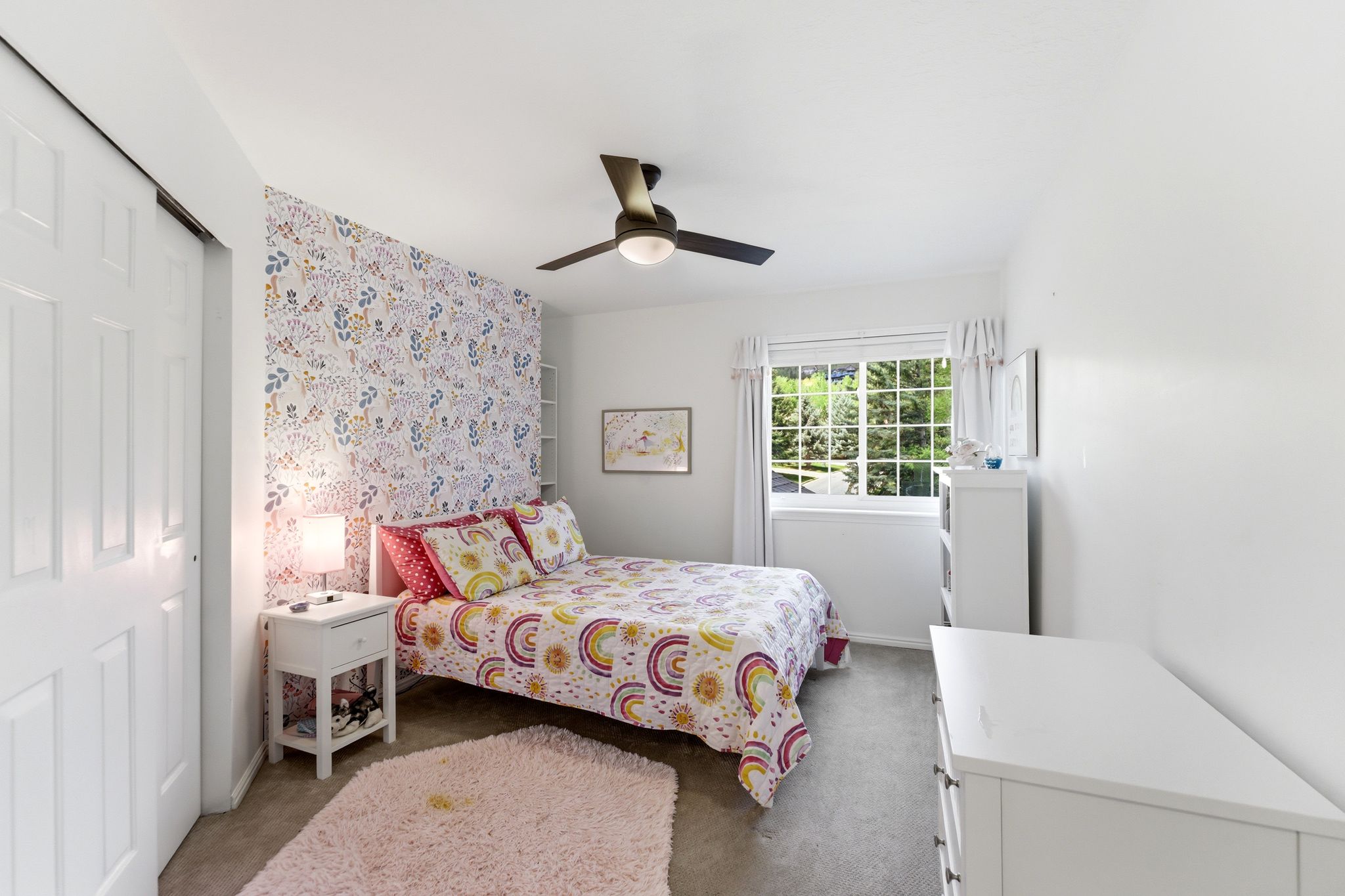 Upper Bedroom 2 featuring a decorative accent wall, ceiling fan with integrated lighting, and a white framed window