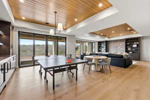 Spacious living area featuring wood-finish flooring, a wood-paneled ceiling detail with recessed lighting, and built-in shelving