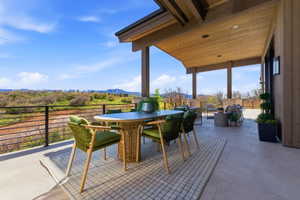 Expansive covered patio featuring large format tile flooring, a natural wood ceiling with recessed lighting, and a contemporary metal railing