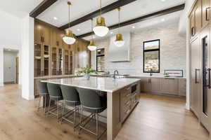 Gourmet kitchen with an expansive center island, quartz countertops, custom cabinetry, built-in appliances, and wood-finish flooring