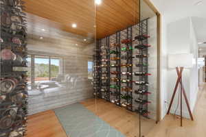 Glass-enclosed wine cellar featuring extensive built-in metal racking, wood-finish flooring, and a slat wood ceiling