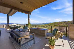 Expansive covered patio featuring a wood-finish ceiling, stone columns, and large format tile flooring
