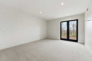 Spacious interior room featuring light-toned carpet flooring and recessed ceiling lighting