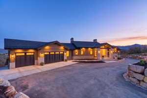 Ranch-style residence featuring a dark shingle roof, wood siding, and stone accents