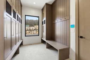 Custom built-in cabinetry with metal accents, integrated bench seating, and an accent window with a stone retaining wall backdrop