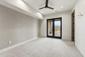 Spacious interior featuring patterned accent wall, recessed lighting, ceiling fan, plush carpet flooring, and black framed glass doors leading to exterior