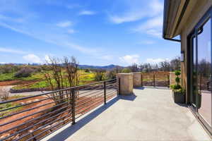 Expansive outdoor deck featuring light-toned large format tile, a horizontal bar railing system, and stone-clad columns