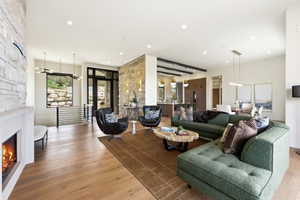 Open-concept living space featuring wood-finish flooring, a stone accent wall, a built-in fireplace, and recessed lighting