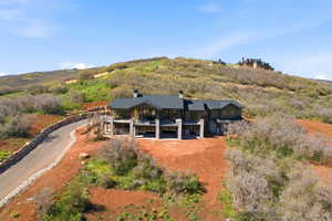 Multi-level residence featuring a dark-toned exterior, multiple balconies, and a stone-lined driveway