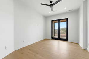 Room featuring light wood-finish flooring, white walls, and a black ceiling fan