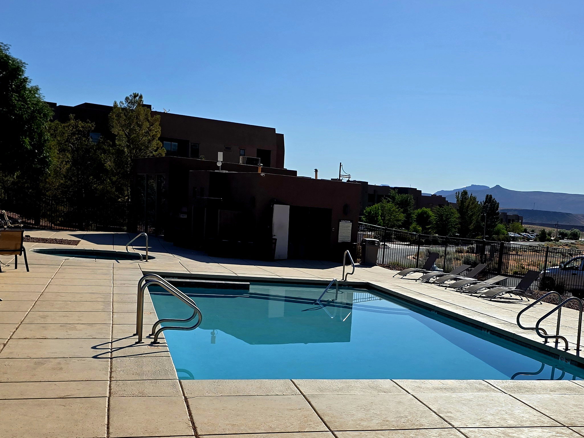 Outdoor swimming pool with integrated spa and surrounding concrete patio \ Community Gym in background.